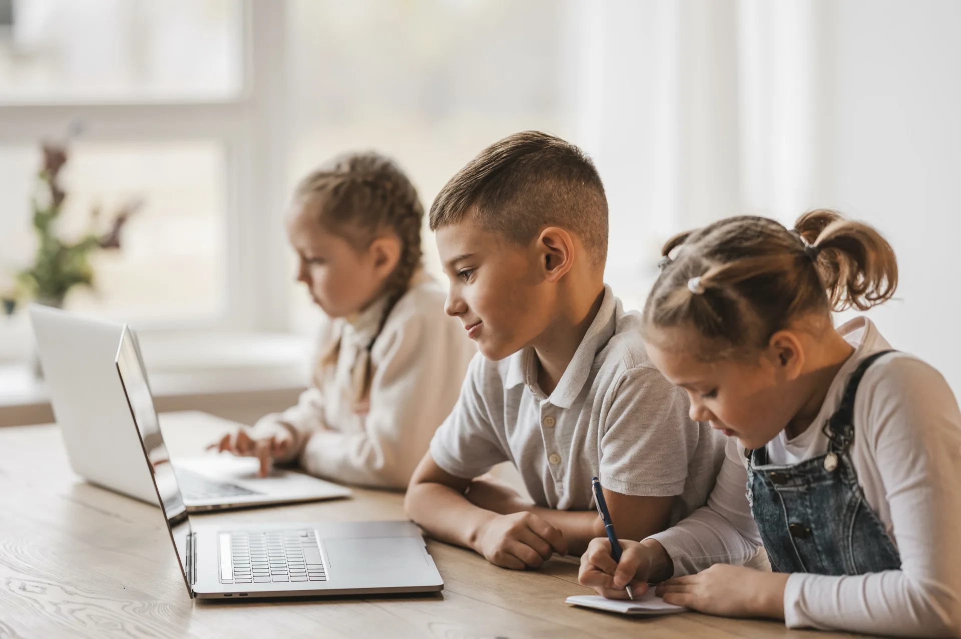 Three children working at two laptops