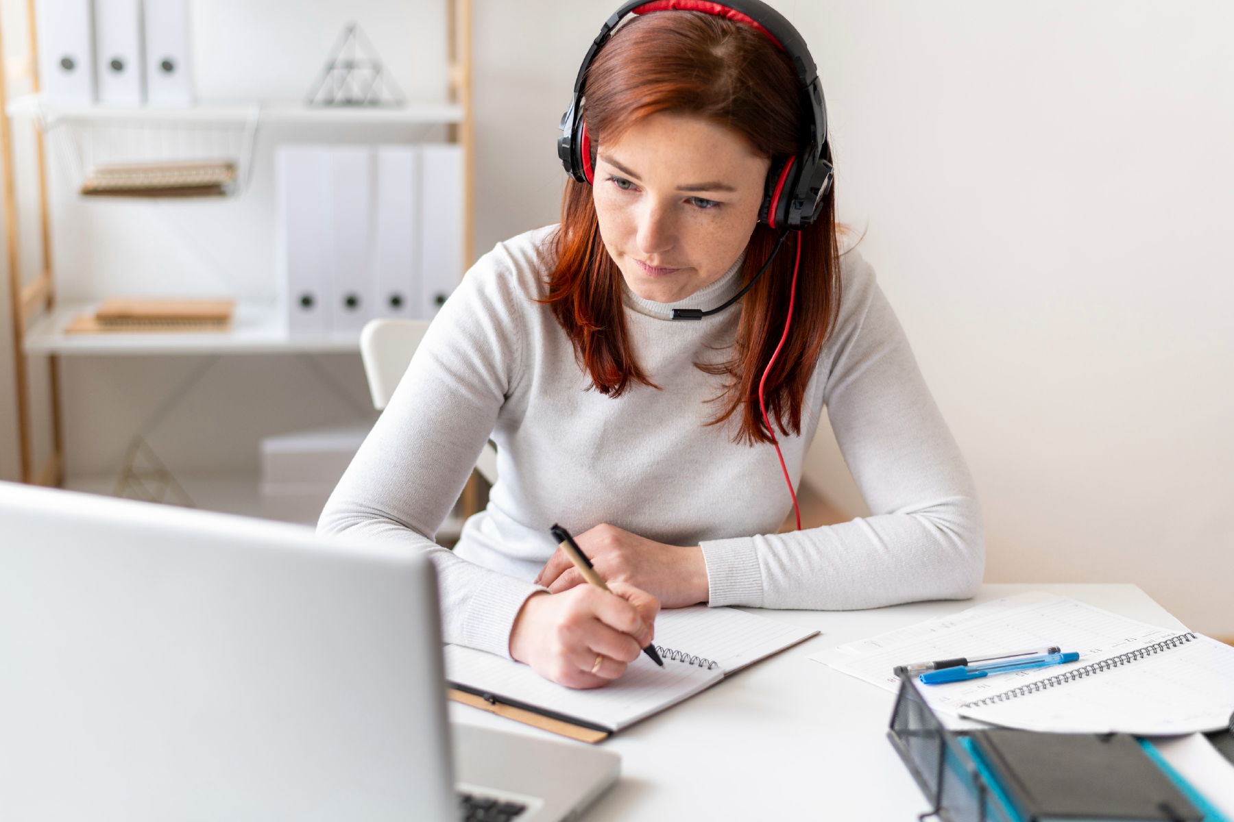 A woman sat at a laptop wearing headphones