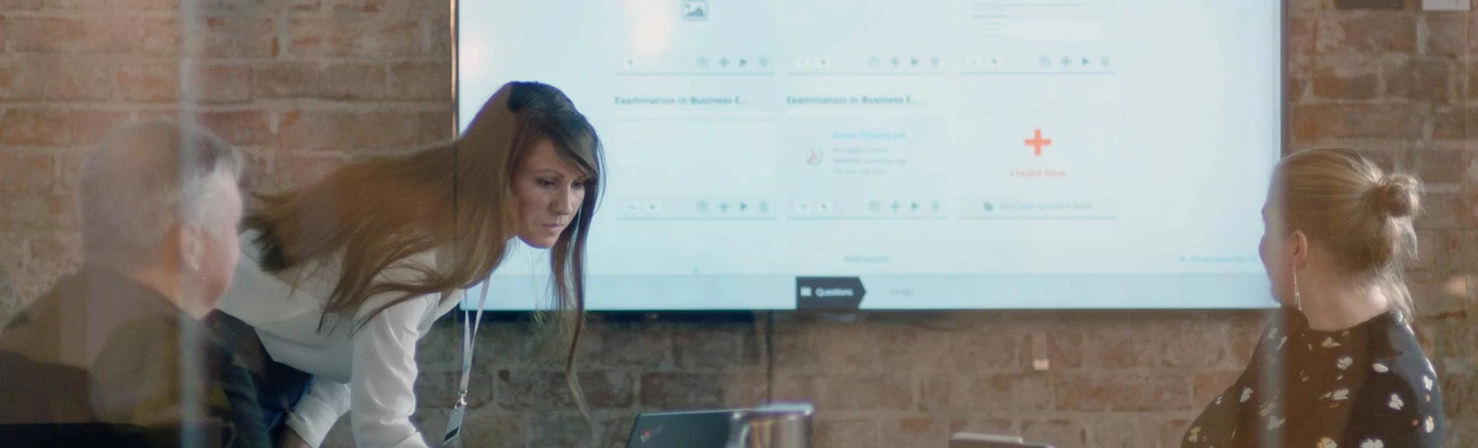 People with laptops and a lady standing next to a presentation screen